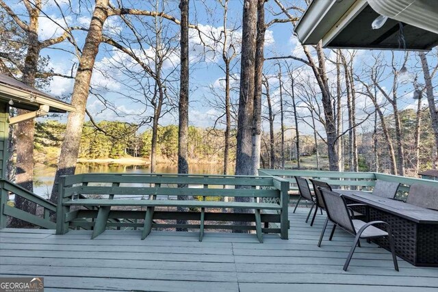 deck with a water view and a wooded view