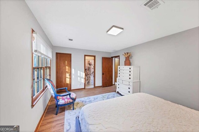 bedroom with baseboards, light wood-type flooring, and visible vents