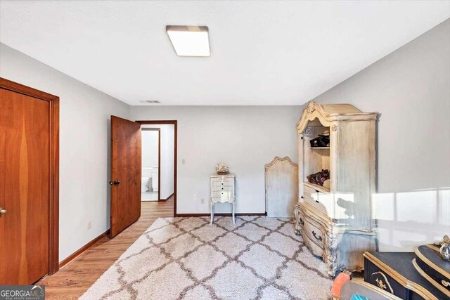 bedroom with visible vents, baseboards, and wood finished floors