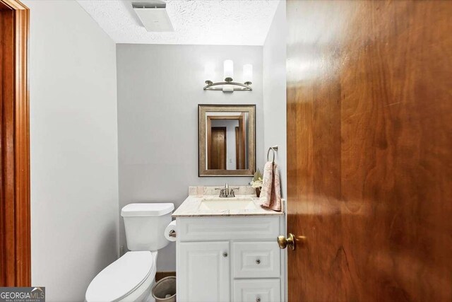 bathroom with visible vents, toilet, vanity, and a textured ceiling