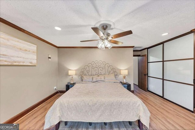 bedroom with crown molding, baseboards, a textured ceiling, and wood finished floors