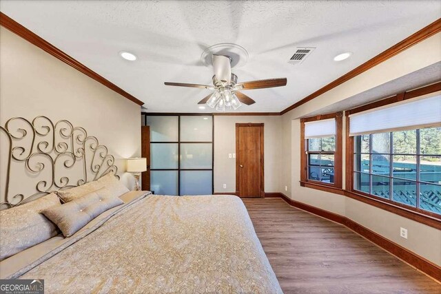unfurnished bedroom featuring baseboards, visible vents, ornamental molding, and wood finished floors