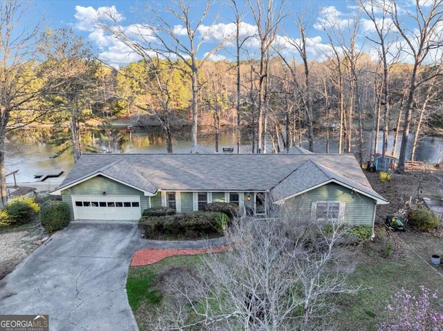 single story home with concrete driveway, a water view, roof with shingles, and an attached garage