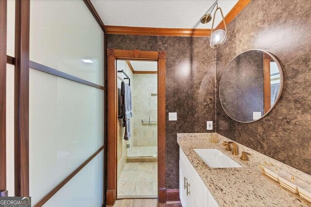full bathroom featuring vanity, crown molding, a stall shower, and a textured ceiling