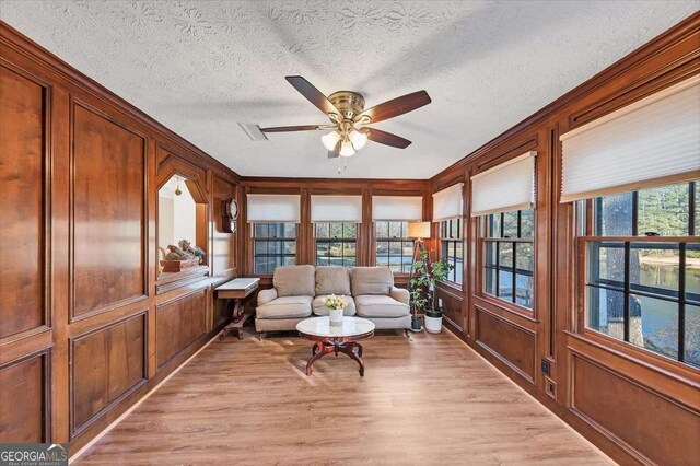 sitting room featuring light wood-style flooring, visible vents, a textured ceiling, and ceiling fan