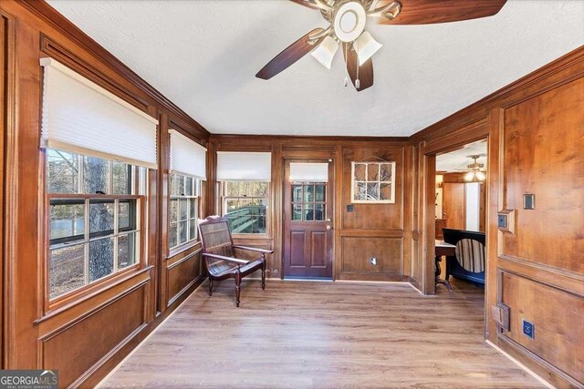 sunroom / solarium with a textured ceiling, wood finished floors, and wood walls
