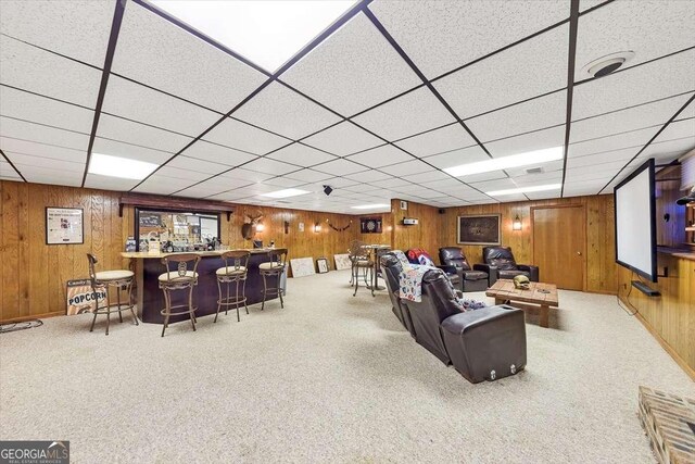 living area with a bar, carpet floors, and wood walls