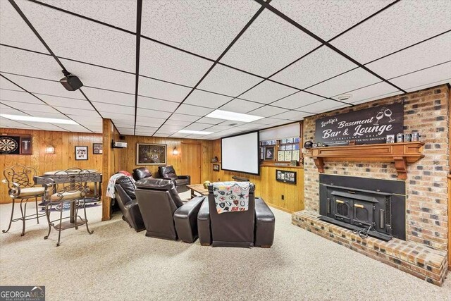carpeted living room with a fireplace and wooden walls