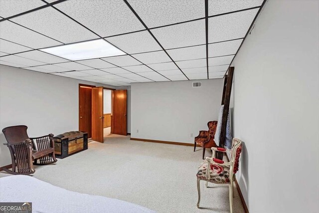interior space with baseboards, visible vents, a drop ceiling, and carpet