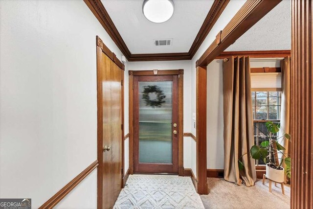doorway to outside with light carpet, crown molding, baseboards, and visible vents