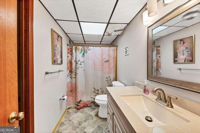 full bathroom featuring curtained shower, a drop ceiling, toilet, and vanity