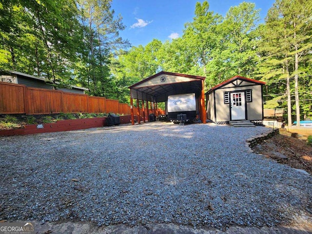 exterior space featuring a shed, driveway, a carport, and fence