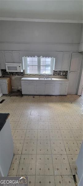 807 Elizabeth St, Waycross, GA 31503 - kitchen with light floors, a sink, white microwave, and crown molding