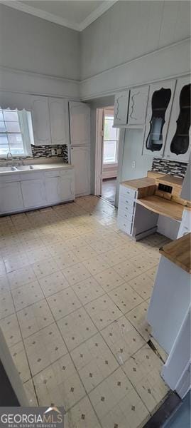 807 Elizabeth St, Waycross, GA 31503 - kitchen with a sink, white cabinetry, light floors, and ornamental molding