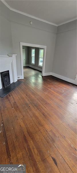 807 Elizabeth St, Waycross, GA 31503 - unfurnished living room featuring baseboards, a fireplace with raised hearth, ornamental molding, and wood-type flooring
