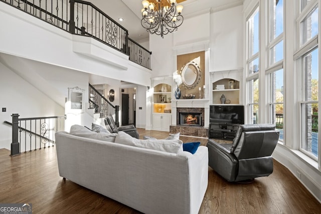 3491 Falls Branch Ct, Buford, GA 30519 - living room with a high ceiling, built in features, a chandelier, wood finished floors, and baseboards