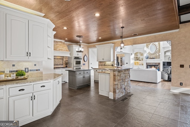 3491 Falls Branch Ct, Buford, GA 30519 - kitchen with wood ceiling, oven, a kitchen island, a glass covered fireplace, and open floor plan