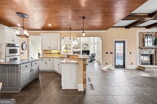 3491 Falls Branch Ct, Buford, GA 30519 - kitchen with open floor plan, a stone fireplace, double oven, a sink, and wooden ceiling