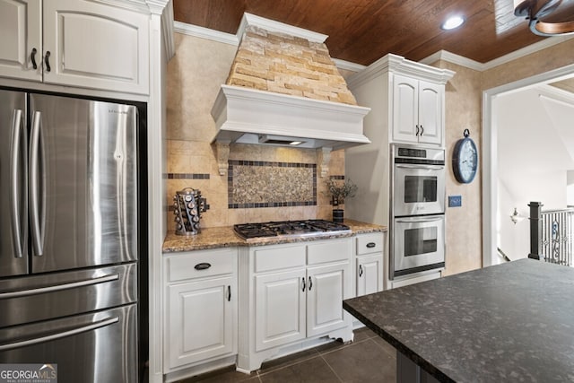 3491 Falls Branch Ct, Buford, GA 30519 - kitchen with appliances with stainless steel finishes, premium range hood, dark tile patterned flooring, backsplash, and white cabinets