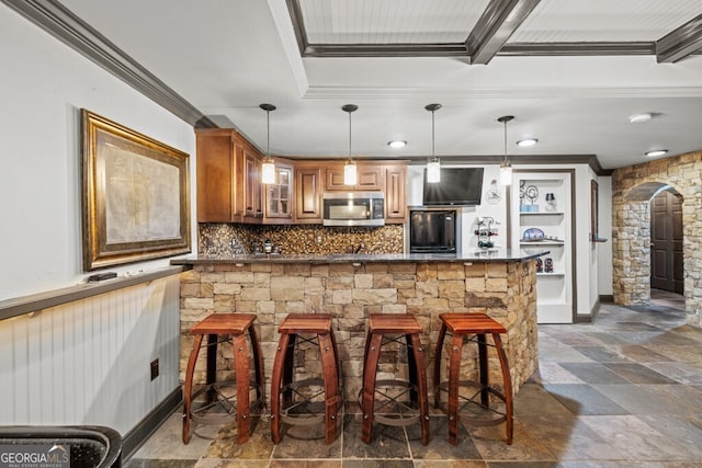3491 Falls Branch Ct, Buford, GA 30519 - kitchen with stainless steel microwave, black refrigerator, crown molding, brown cabinetry, and a kitchen breakfast bar