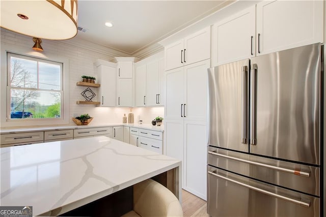 kitchen featuring backsplash, open shelves, light stone countertops, white cabinets, and freestanding refrigerator