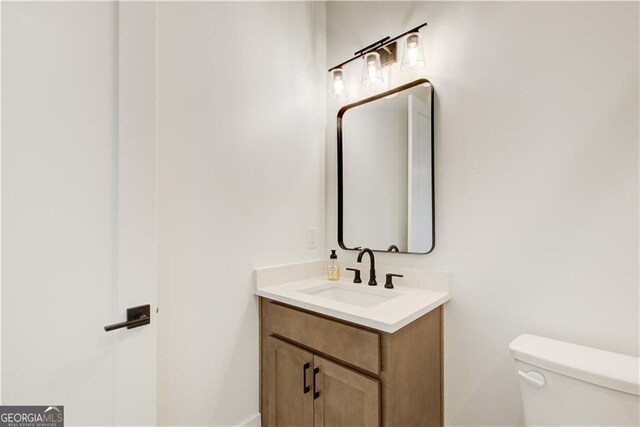 half bath featuring vanity and toilet