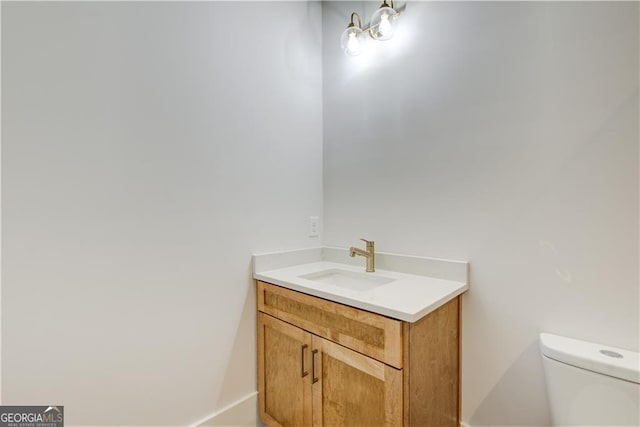 bathroom featuring toilet, baseboards, and vanity