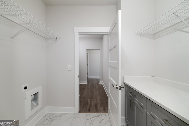 washroom with cabinet space, baseboards, electric dryer hookup, and marble finish floor