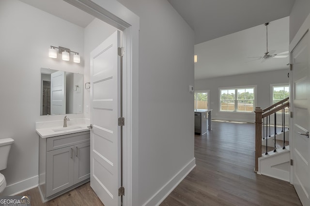 interior space with dark wood-style flooring, a sink, baseboards, and stairs