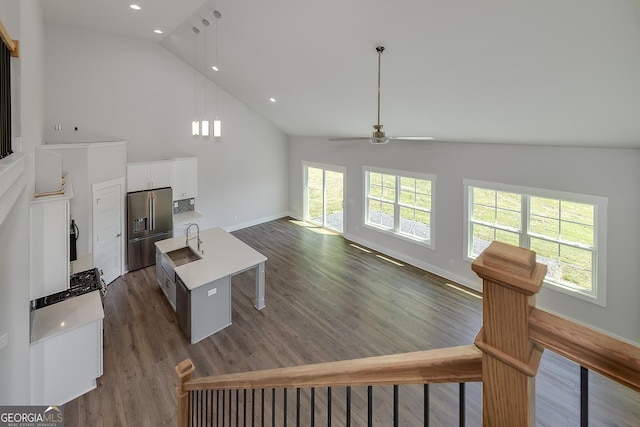 living area with dark wood-style flooring, ceiling fan, high vaulted ceiling, and baseboards