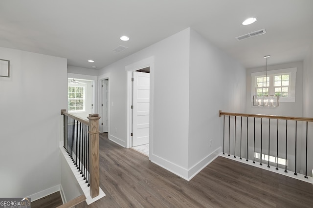 corridor featuring an upstairs landing, visible vents, an inviting chandelier, and wood finished floors