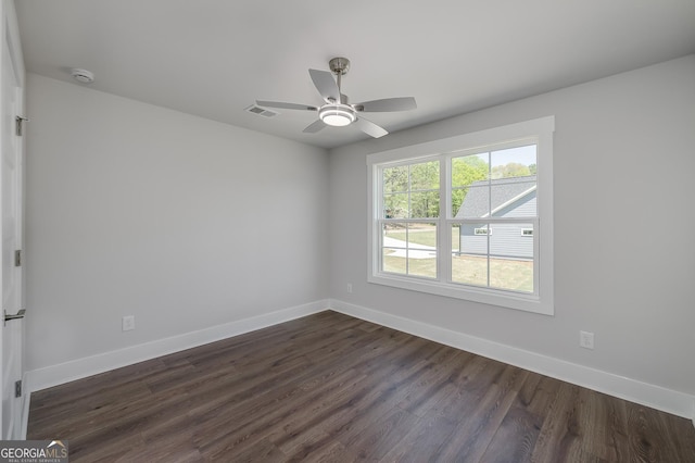 spare room featuring baseboards, dark wood-style floors, and visible vents