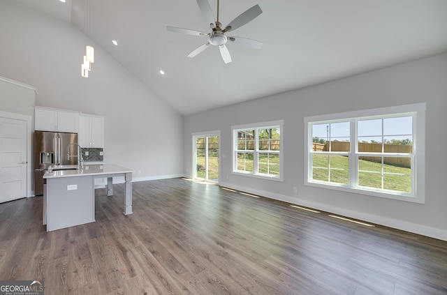 unfurnished living room featuring baseboards, a sink, ceiling fan, dark wood-type flooring, and high vaulted ceiling