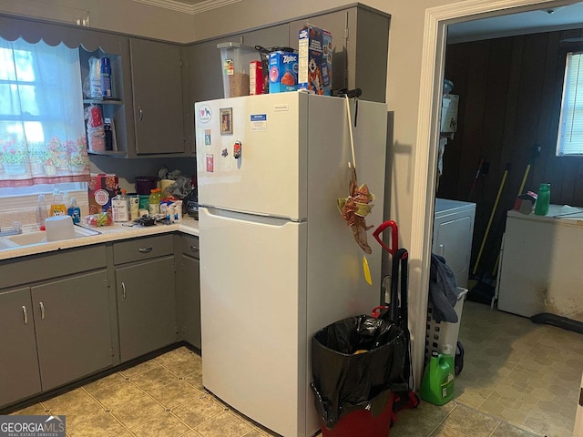 kitchen with light countertops, gray cabinets, a sink, freestanding refrigerator, and washer / clothes dryer
