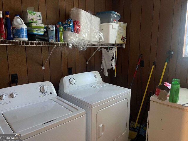 laundry room with washing machine and clothes dryer, wood walls, and laundry area