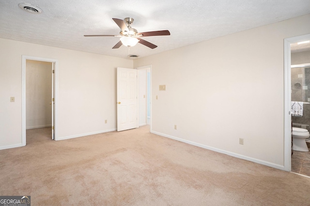 unfurnished bedroom with connected bathroom, light colored carpet, baseboards, and visible vents