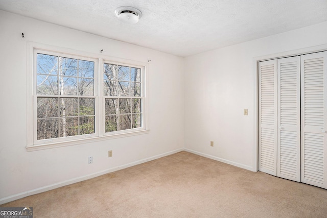 unfurnished bedroom with light colored carpet, baseboards, a closet, and multiple windows