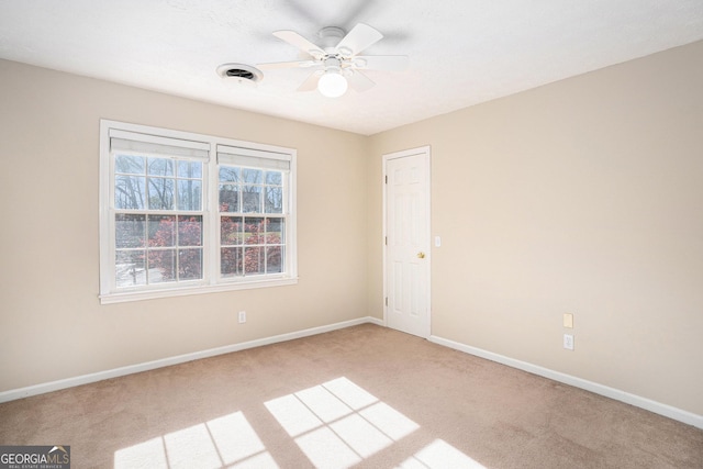 spare room with baseboards, a ceiling fan, and light colored carpet