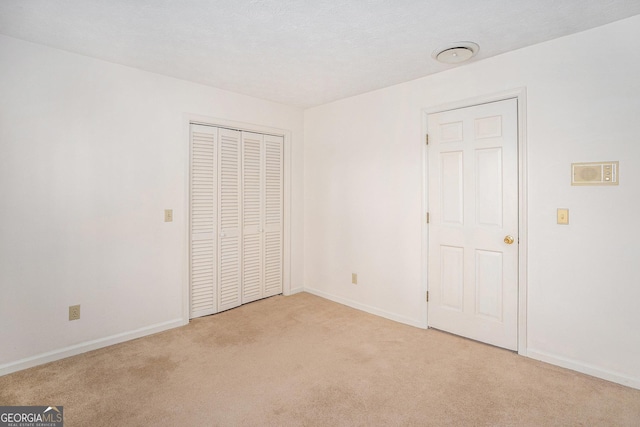 unfurnished bedroom featuring baseboards, light carpet, and a closet