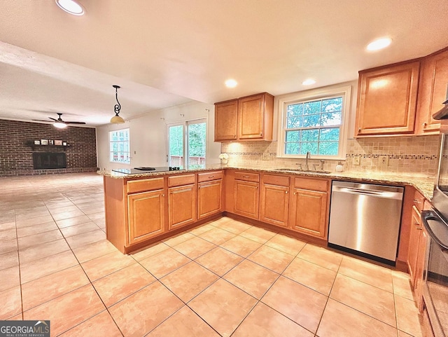 kitchen featuring a brick fireplace, a peninsula, open floor plan, a sink, and black appliances