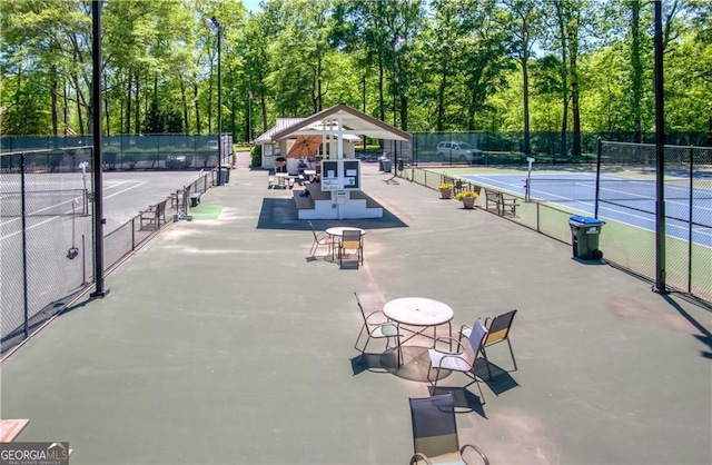 surrounding community featuring a tennis court and fence
