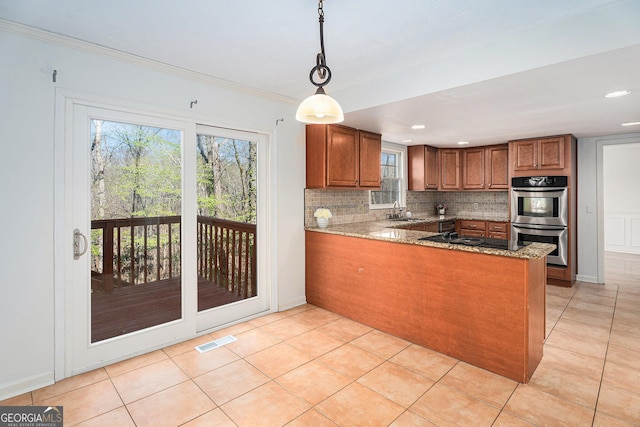 kitchen with brown cabinetry, visible vents, a peninsula, double oven, and light stone counters