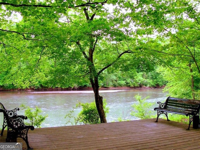 view of dock with a water view and a forest view