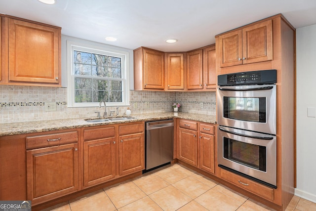 kitchen with a sink, light tile patterned floors, stainless steel appliances, and brown cabinets