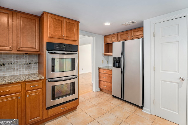 kitchen featuring brown cabinetry, appliances with stainless steel finishes, and light tile patterned floors