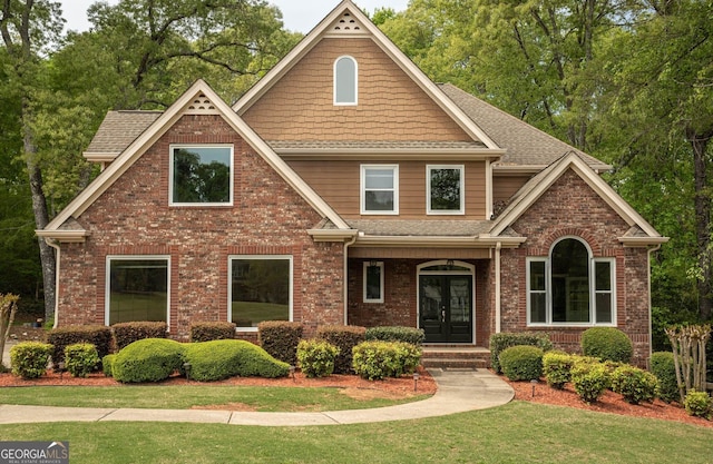craftsman-style home featuring brick siding, french doors, and a shingled roof
