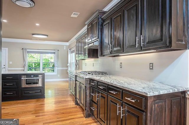 kitchen featuring crown molding, light wood-style floors, under cabinet range hood, appliances with stainless steel finishes, and baseboards