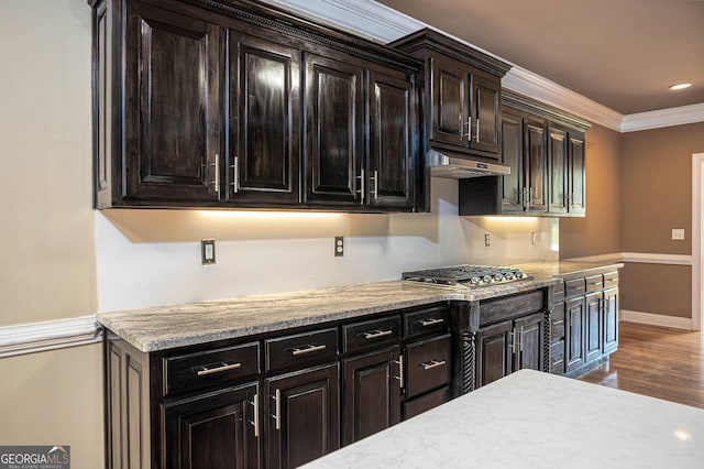 kitchen featuring stainless steel gas stovetop, ornamental molding, under cabinet range hood, wood finished floors, and baseboards