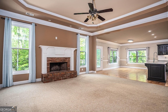 unfurnished living room with ornamental molding, light carpet, a sink, a brick fireplace, and baseboards