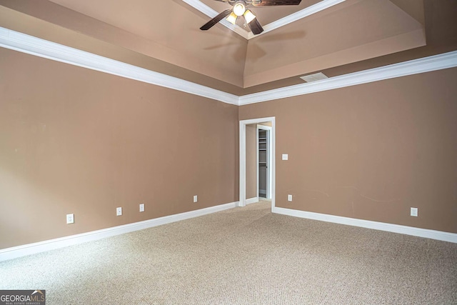 carpeted empty room with crown molding, a tray ceiling, a ceiling fan, visible vents, and baseboards
